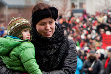 Frau mit Kind im Arm wartet auf Lohngleichheit