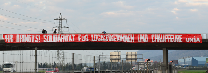 Transparent über Autobahn: Ihr bringt's! Solidarität für Logistikerinnen und Chauffeure - Unia