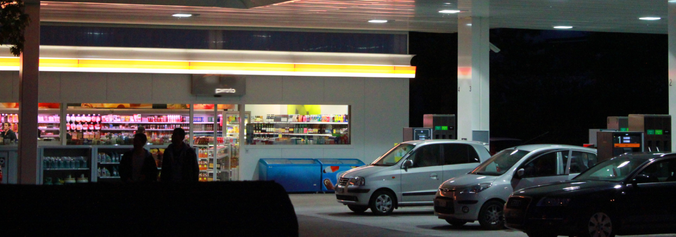 Eine Tankstelle mit einem Shop bei Nacht.