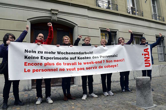 Sept secrétaires syndicaux tiennent une banderole devant un bâtiment à Berne
