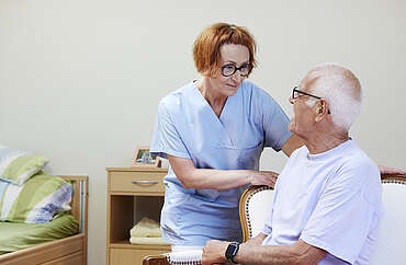 Eine Pflegefachperson kümmert sich um einen älteren Mann
