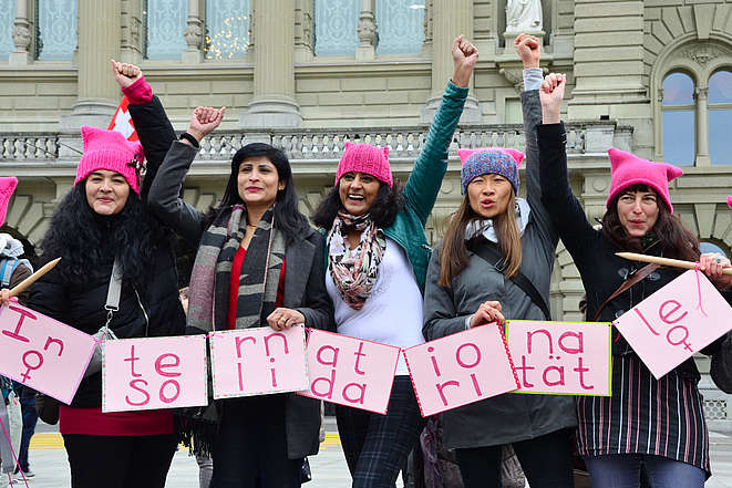5 Frauen mit erhobner Faust und Kartons mit der Aufschrift: Internationale Solidarität
