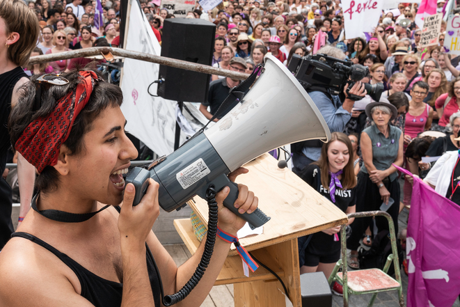 Une jeune femme s'adresse à une foule avec un mégaphone lors de la grève des femmes en 2019 à St-Gall