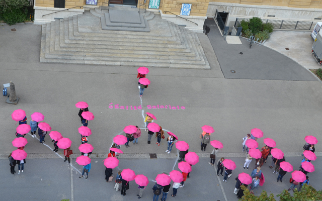 Frauen mit pinken Regenschirmen bilden das Wort NOW