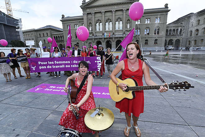 2 musiciennes devant des femmes sur la place fédérale avec banderole: Pour les femmes: du respect, pas de travail au rabais! 