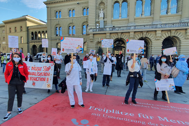 Pflegende in Berufskleidung mit Schilder an einem Protest auf dem Bundesplatz