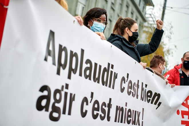 Des soignant-e-s et d'autres employé-e-s dans des métiers essentiels protestent à Bienne avec une banderole (Applaudir c'est bien, agir c'est mieux!)