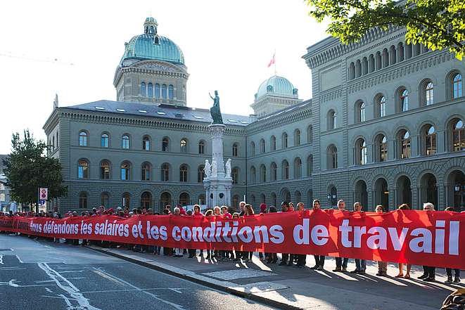 Les 200 personnes forment la ligne rouge avec une longue banderole: Nous défendons les salaires et les conditions de travail