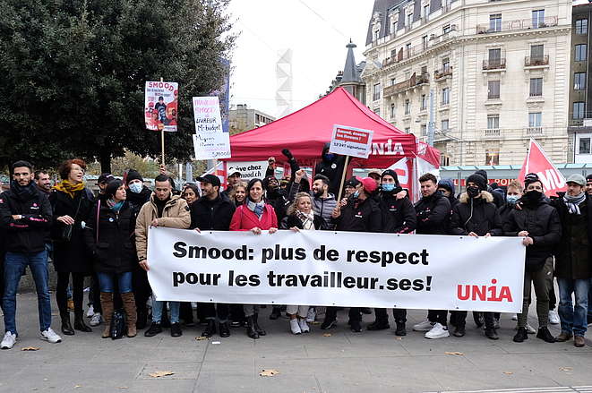 Des représentant-e-s des livreuses et livreurs Smood et des syndicats derrière une banderole.