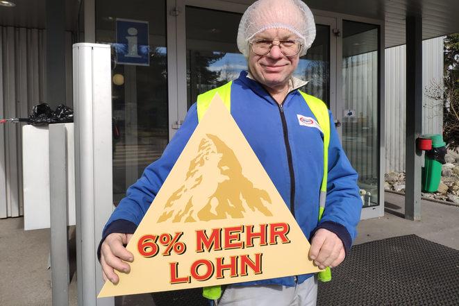 Angestellter von Mondelez mit Toblerone-Schild: 6% mehr Lohn 