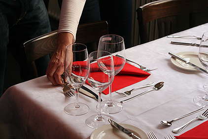 Hand deckt Tisch in Restaurant