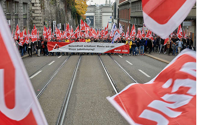Bauarbeiter fordern an einem Umzug durch Zürich: Gesundheit schützen! Rente mit 60! Stopp Lohndumping!