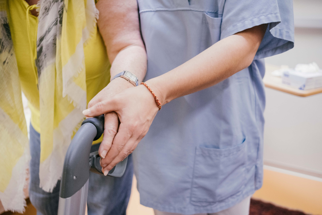 Une infirmière soutient une patiente par la main