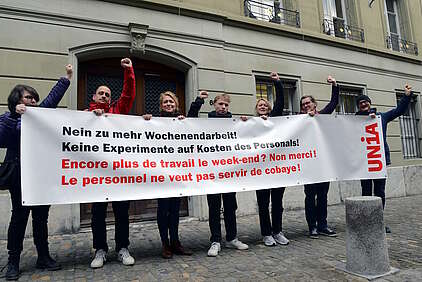 Sieben Gewerkschafterinnen und Gewerkschafter halten weisses Transparent vor einem Gebäude in Bern