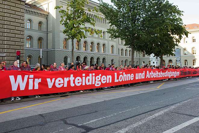 200 Menschen halten das grosse Transpi mit der Aufschrift: Wir verteidigen Löhne und Arbeitsbedingungen