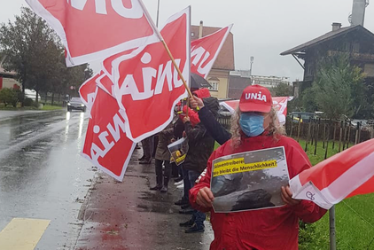 Protestaktion an einer Strasse in triefendem Regen mit Schild  «Sklaventreiberei. Wo bleibt die Menschlichkeit?»
