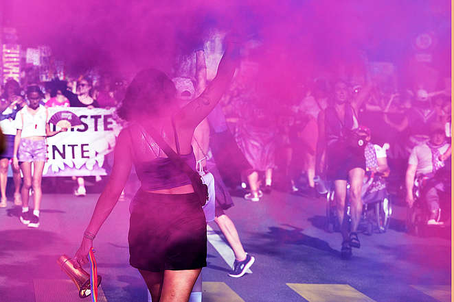 Eine Frau demonstriert in lilafarbenem Rauch.