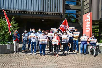 Des membres du groupe professionel Coop du syndicat Unia se tiennent devant le secrétariat central d'Unia avec des masques de protection