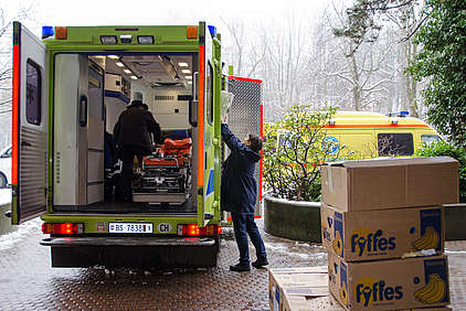 Der Ambulanzwagen mit offenen Türen (Blick auf die Bahre) wird gepackt. 