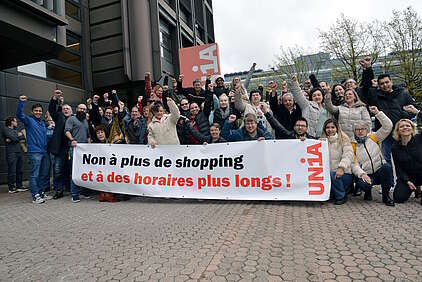 Les participant-e-s de la conférence de branche du commerce de détail portent une banderole sur laquelle est inscrit «Non à davantage de shopping et à des horaires plus longs!»