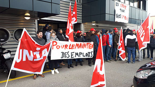 Les employé-e-s de Symetis devant le bâtiment avec des banderoles.