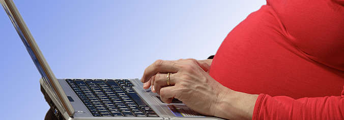 Schwangere Frau arbeitet am Computer