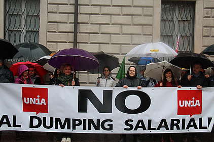 Menschen im Regen mit Transparent «Nein zum Lohndumping»