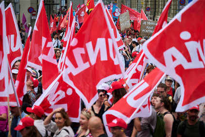 Des participant-e-s portent des drapeaux d'Unia dans la manifestation pour les salaires du 16 septembre 2023 à Berne