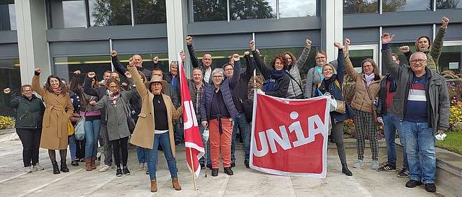 Unia-Mitglieder aus dem Detailhandel mit Unia-Fahne und erhobenen Fäusten