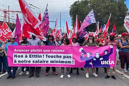 Manifestant-e-s avec bannière: Non à Ettlin! Touche pas à notre salaire minimum!