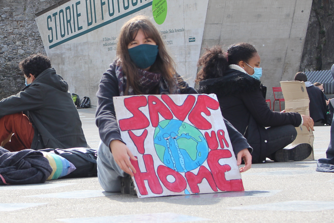  Sit in a Bellinzona: una giovane donna è seduta per terra con un cartello «Save your home»