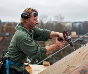 Ouvrier avec une perceuse sur un toit