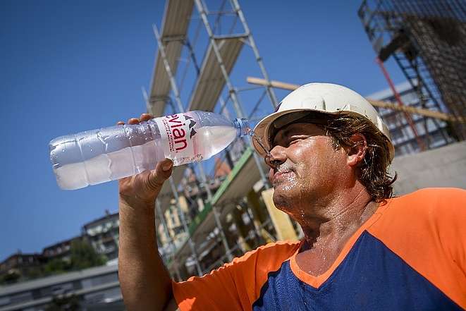 Ein Bauarbeiter kühlt sich während der Arbeit mit Wasser ab