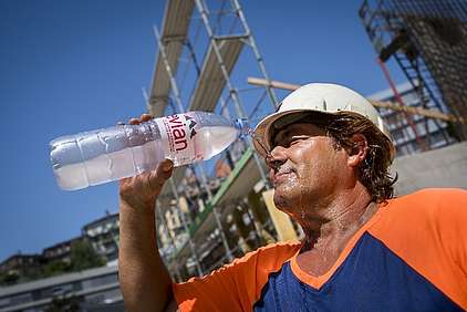 Ein Bauarbeiter kühlt sich während der Arbeit mit Wasser ab