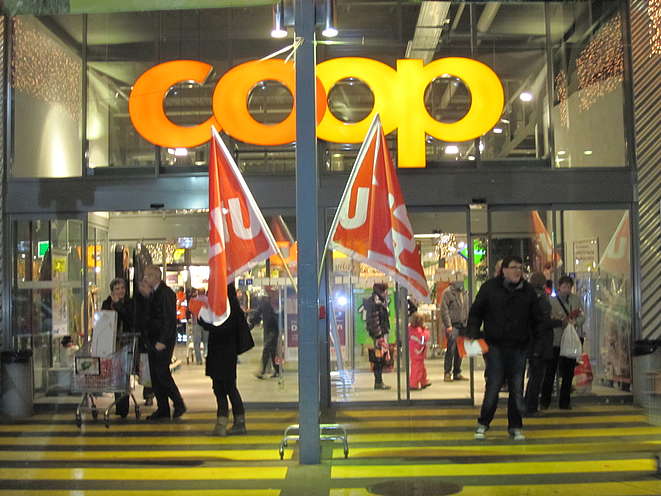 Des drapeaux Unia devant un magasin Coop