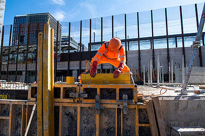 Ein Bauarbeiter hält eine Spanholzplatte in den Händen bei der Arbeit auf einer Baustelle in Genf