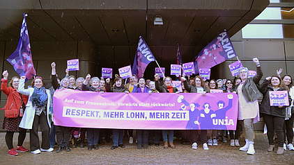 60 Unia-Gewerkschafterinnen halten ein Transparent mit dem Aufruf zum Frauenstreik 2023 hoch.