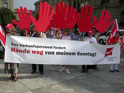 Protest von Verkäuferinnen mit einem Transparent gegen Arbeit am Sonntag
