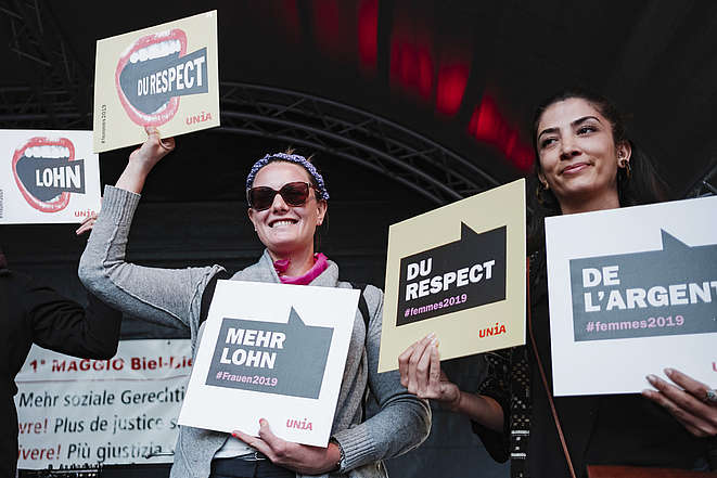 2 Frauen mit Schilder «Du respect», «Mehr Lohn» ect.